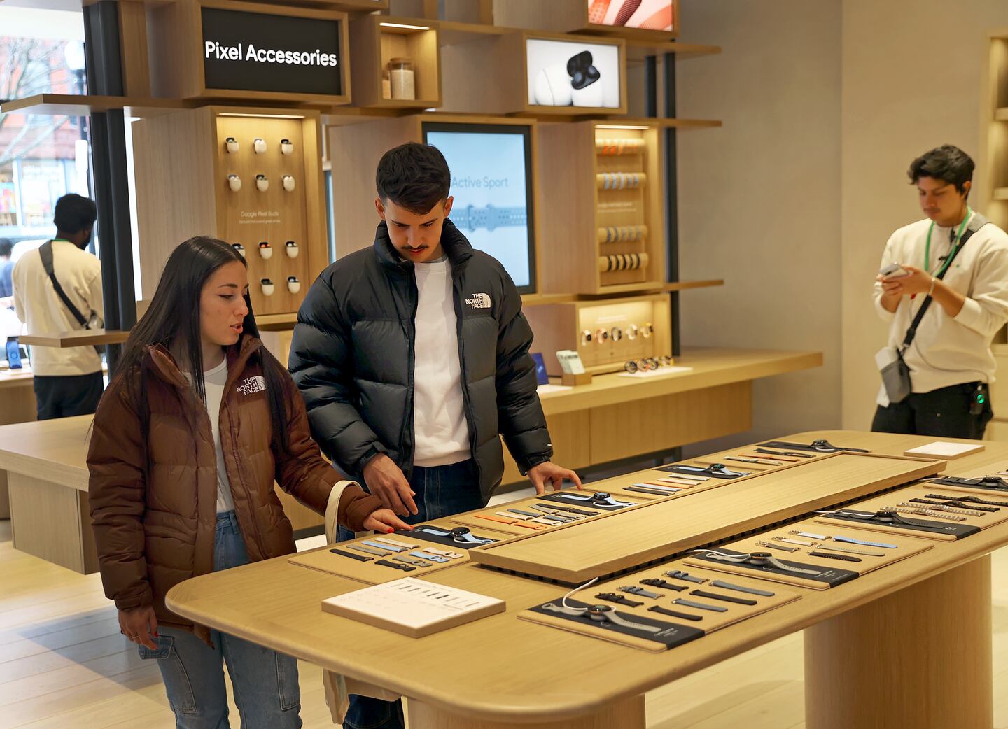 Customers Federica Risuglia (left) and Jose Moreno look at products at the Google Store in Boston.
