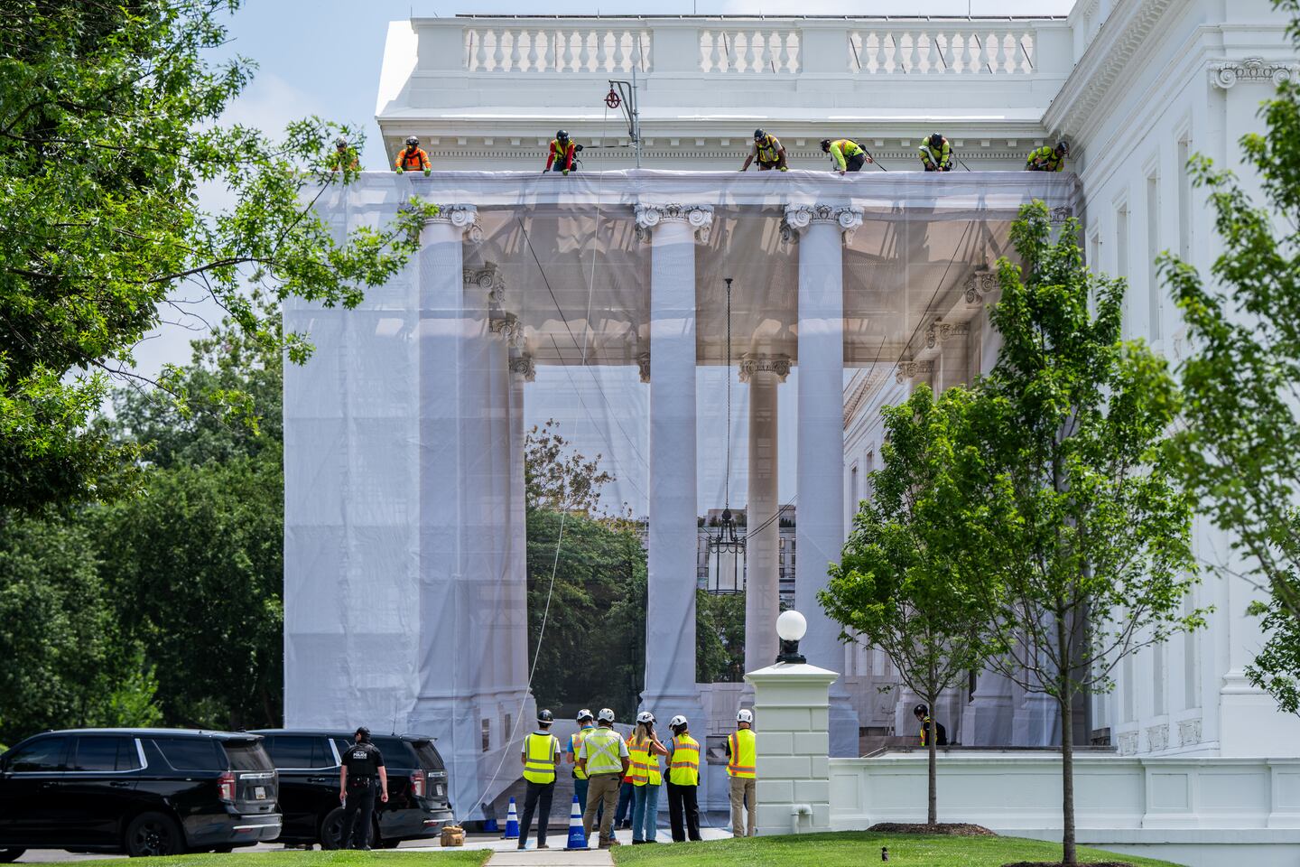 Workers put up a tarp to cover the scaffolding on the North Portico of the White House.